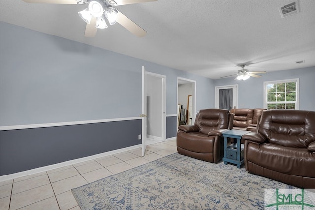 living room featuring light tile patterned flooring, a textured ceiling, and ceiling fan