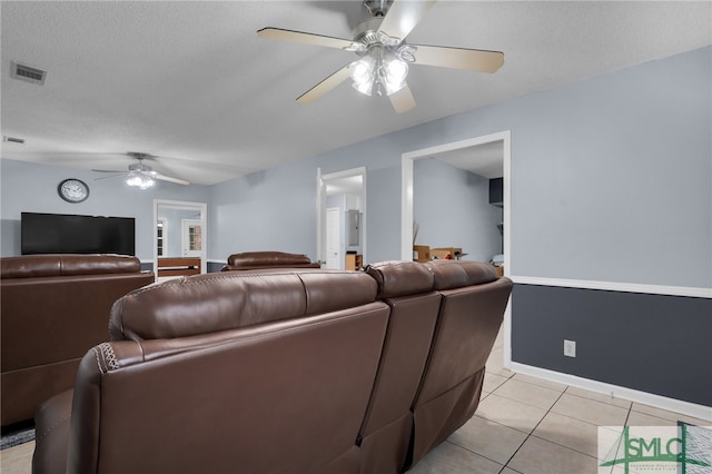 tiled living room with ceiling fan and a textured ceiling