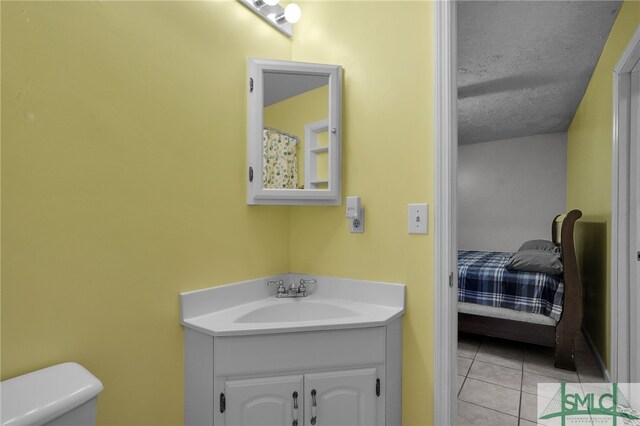 bathroom with tile patterned floors, vanity, toilet, and a textured ceiling