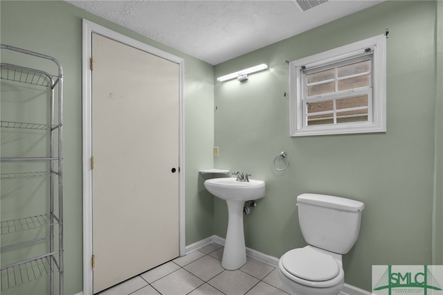 bathroom with tile patterned flooring, a textured ceiling, and toilet