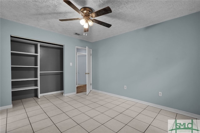 unfurnished bedroom with a closet, light tile patterned floors, a textured ceiling, and ceiling fan