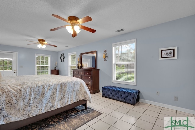 tiled bedroom with ceiling fan and a textured ceiling