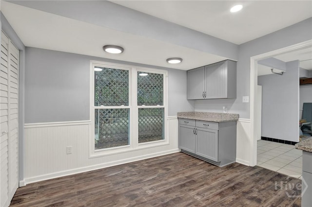 46 River Oaks Rd, Savannah, GA 31410 - kitchen featuring gray cabinets, dark wood finished floors, a wainscoted wall, light stone countertops, and baseboards