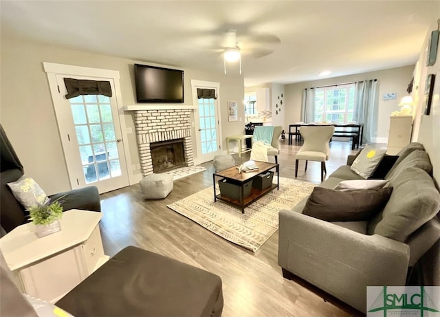 living room with ceiling fan, a fireplace, and light hardwood / wood-style floors