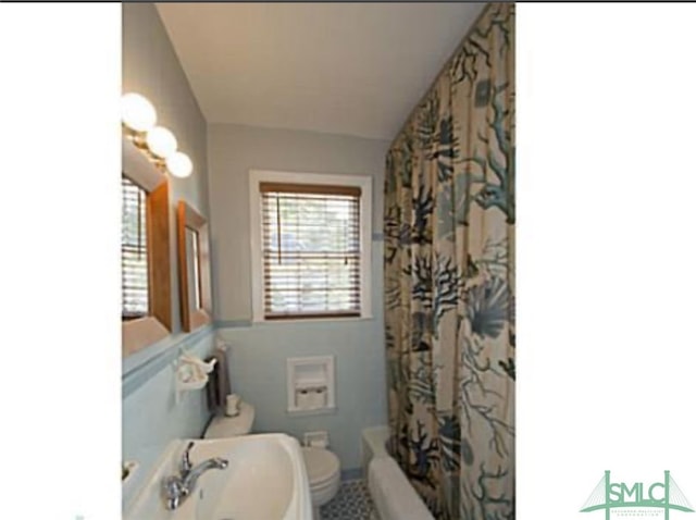 bathroom featuring toilet and shower / tub combo with curtain