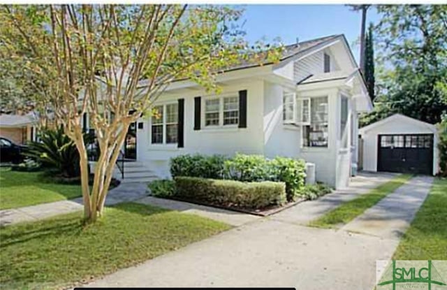 view of front facade featuring a garage, a front yard, and an outdoor structure