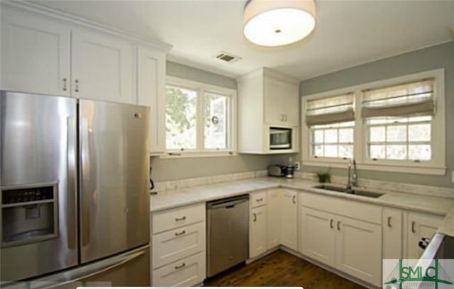 kitchen with appliances with stainless steel finishes, dark wood-type flooring, sink, and white cabinetry