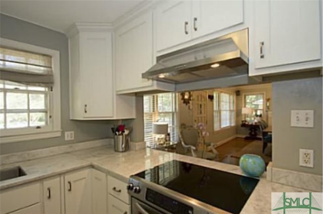 kitchen featuring light stone counters, black stove, a wealth of natural light, and white cabinetry