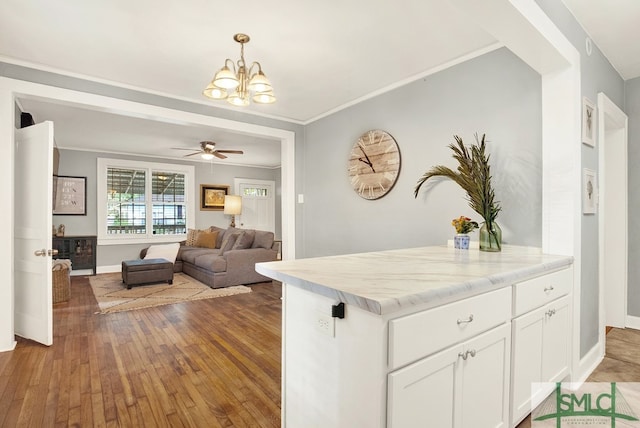 kitchen with pendant lighting, crown molding, dark hardwood / wood-style flooring, light stone counters, and white cabinets