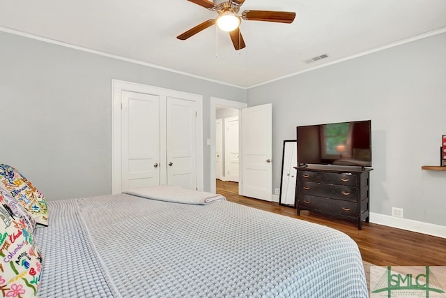 bedroom with a closet, dark hardwood / wood-style floors, crown molding, and ceiling fan