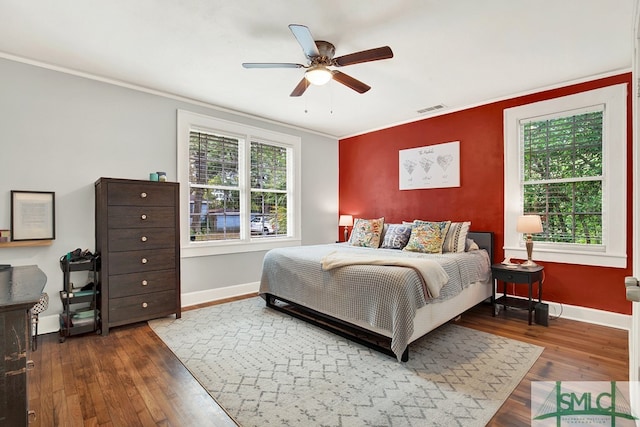 bedroom with ceiling fan, crown molding, and dark wood-type flooring