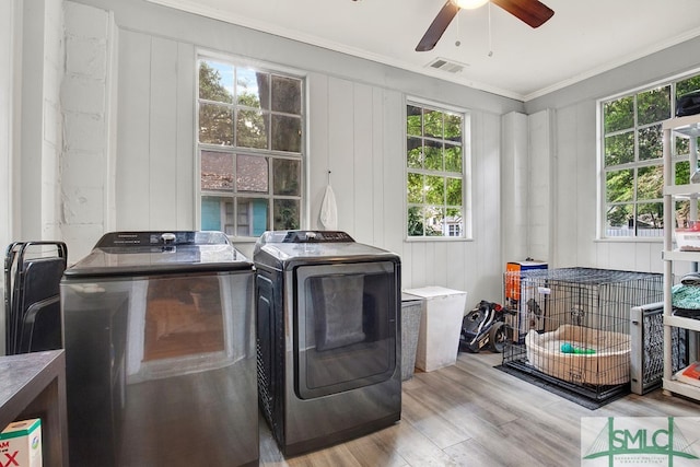 laundry room with washing machine and dryer, crown molding, light wood-type flooring, and a healthy amount of sunlight