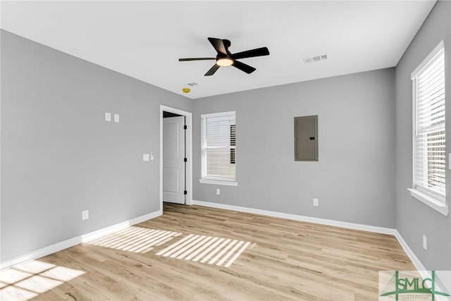 spare room with electric panel, ceiling fan, and light hardwood / wood-style floors