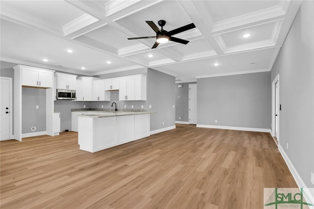 kitchen with coffered ceiling, sink, ornamental molding, light stone countertops, and white cabinetry