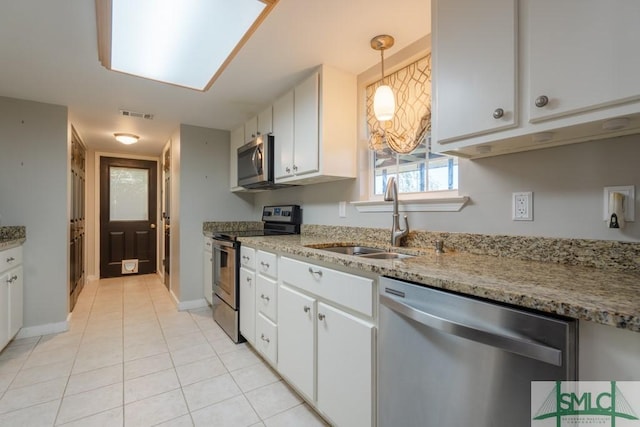 159 E 1st St, Midway, GA 31320 - kitchen featuring appliances with stainless steel finishes, white cabinetry, light tile patterned flooring, light stone counters, and hanging light fixtures