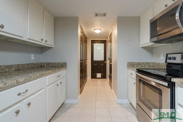 159 E 1st St, Midway, GA 31320 - kitchen with appliances with stainless steel finishes, light tile patterned flooring, white cabinetry, and light stone countertops