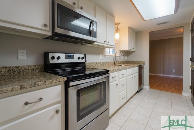 159 E 1st St, Midway, GA 31320 - kitchen with appliances with stainless steel finishes, white cabinetry, light tile patterned floors, and light stone countertops