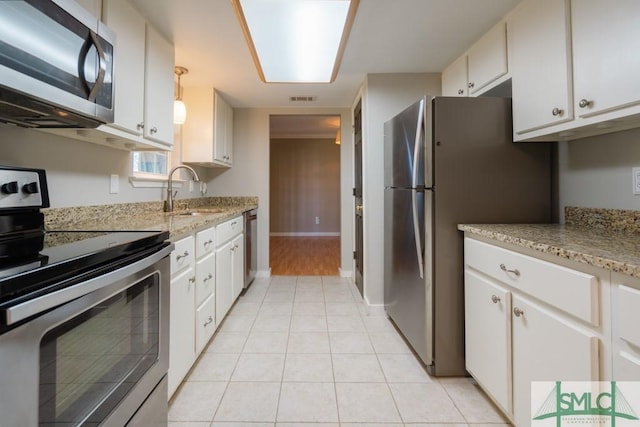 159 E 1st St, Midway, GA 31320 - kitchen featuring stainless steel appliances, light tile patterned flooring, white cabinetry, and light stone countertops