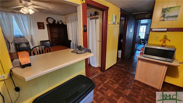 kitchen featuring ceiling fan, wood walls, and dark parquet flooring