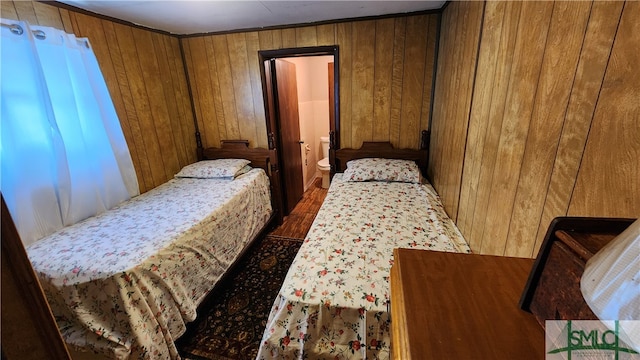 bedroom featuring ornamental molding, hardwood / wood-style flooring, and wood walls