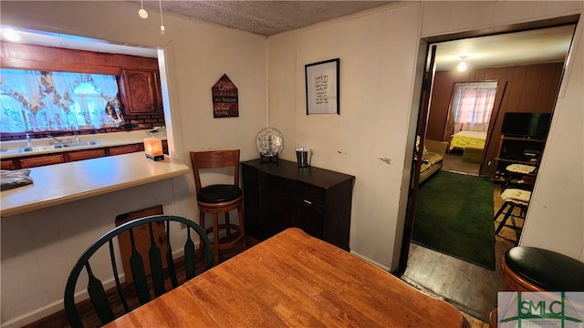 dining area featuring sink, hardwood / wood-style flooring, and a textured ceiling