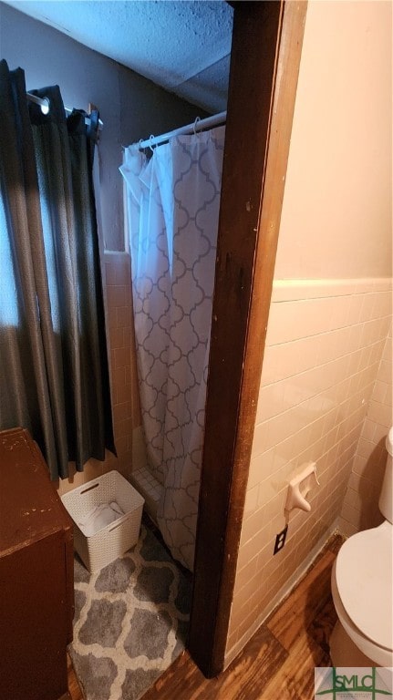 bathroom featuring curtained shower, tile walls, hardwood / wood-style floors, and toilet