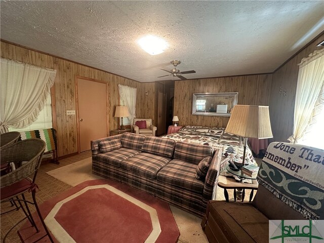 living room featuring ceiling fan, a textured ceiling, and wooden walls