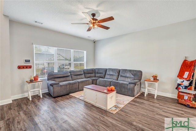 living room with ceiling fan, dark hardwood / wood-style floors, and a textured ceiling