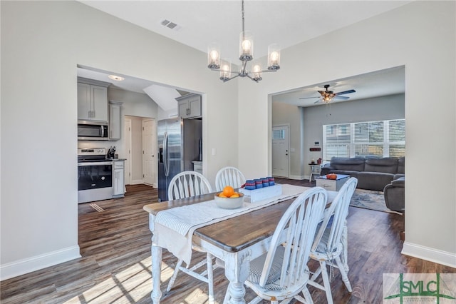 dining space featuring ceiling fan with notable chandelier, dark wood-type flooring, and vaulted ceiling