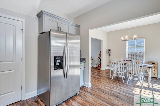 kitchen with hardwood / wood-style floors, gray cabinetry, a chandelier, and stainless steel fridge with ice dispenser