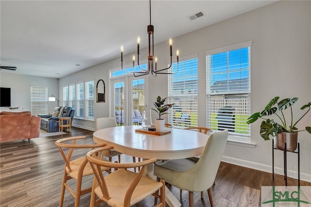 dining space with a notable chandelier, plenty of natural light, and dark wood-type flooring