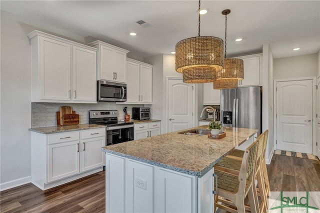 kitchen featuring pendant lighting, sink, a center island with sink, white cabinetry, and stainless steel appliances