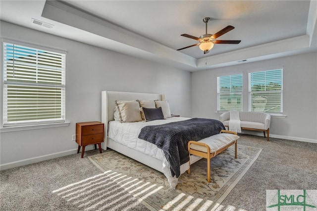 bedroom with ceiling fan, a tray ceiling, and carpet floors