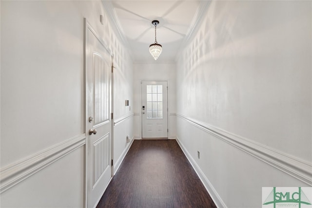 doorway with a notable chandelier, crown molding, and dark wood-type flooring