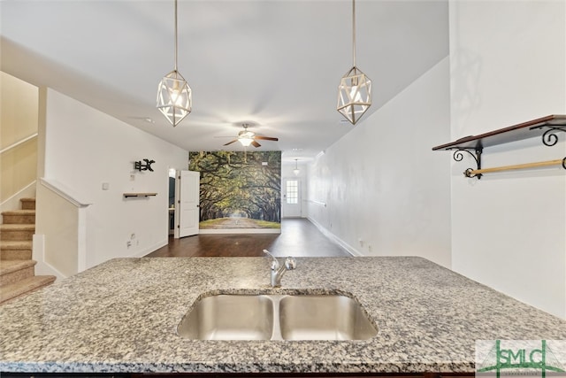 kitchen with hanging light fixtures, sink, dark hardwood / wood-style flooring, and light stone counters