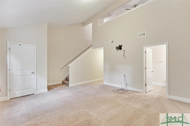 unfurnished living room with light carpet and high vaulted ceiling