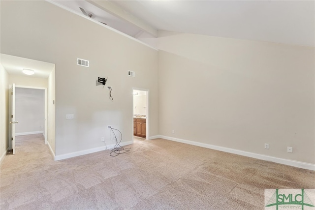 spare room featuring light carpet, beamed ceiling, and high vaulted ceiling