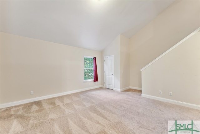 carpeted spare room featuring vaulted ceiling