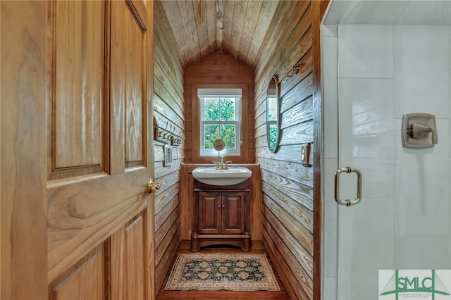 bathroom featuring vanity, wooden walls, a shower with shower door, and vaulted ceiling