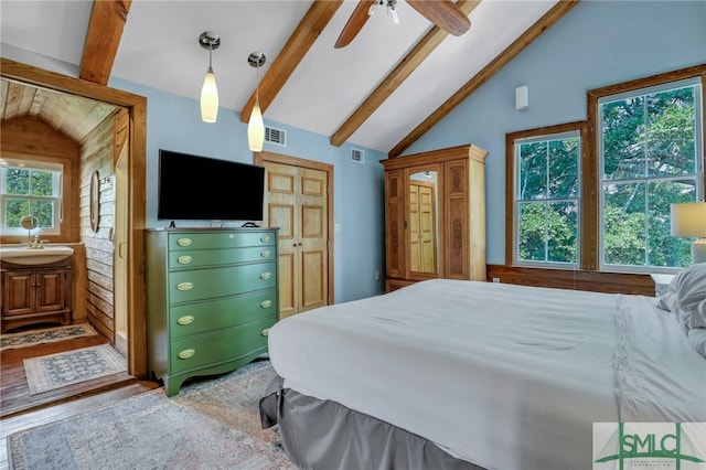 bedroom with lofted ceiling with beams, ceiling fan, hardwood / wood-style floors, sink, and connected bathroom