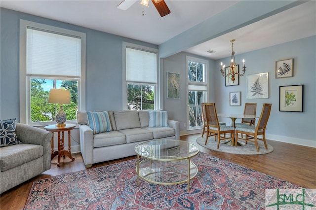 living room with hardwood / wood-style flooring, ceiling fan with notable chandelier, and plenty of natural light