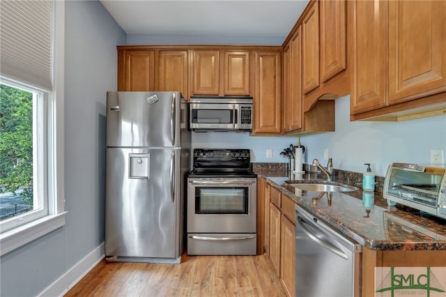 kitchen with dark stone countertops, appliances with stainless steel finishes, plenty of natural light, and sink