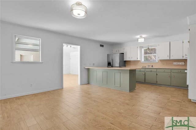 kitchen featuring stainless steel refrigerator with ice dispenser, light hardwood / wood-style flooring, green cabinetry, and sink