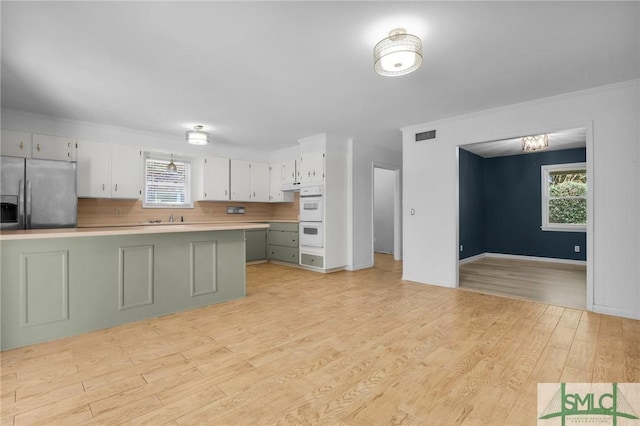 kitchen featuring stainless steel fridge, light wood-type flooring, white cabinetry, and double oven