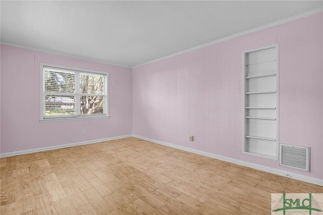 unfurnished room with built in shelves, ornamental molding, and light hardwood / wood-style flooring