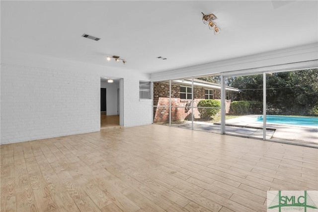 interior space with brick wall and light hardwood / wood-style floors