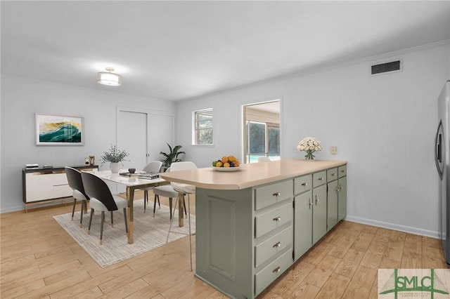 kitchen with kitchen peninsula, light hardwood / wood-style flooring, stainless steel refrigerator, and green cabinets