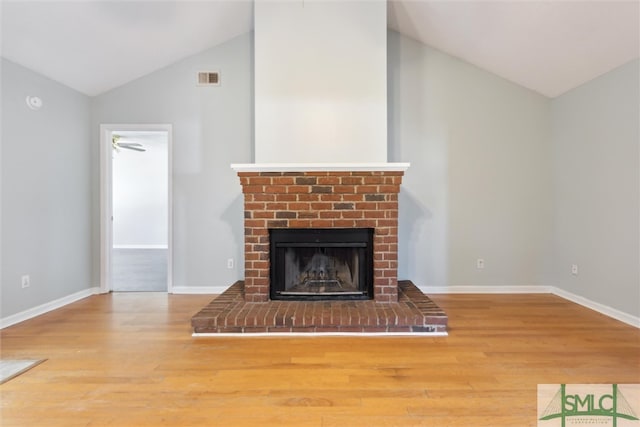 unfurnished living room with wood-type flooring, lofted ceiling, and a brick fireplace