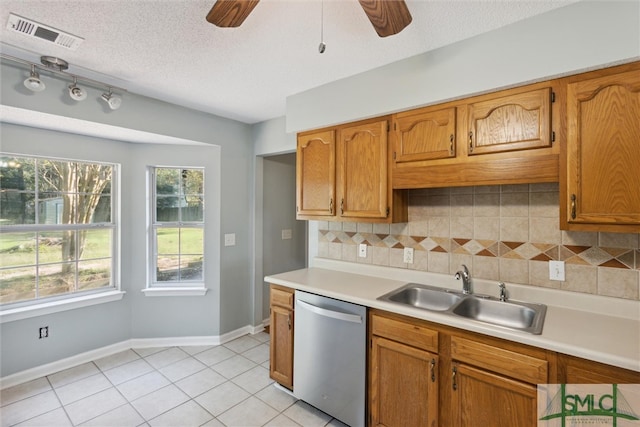 kitchen featuring sink, dishwasher, light tile patterned flooring, a textured ceiling, and decorative backsplash