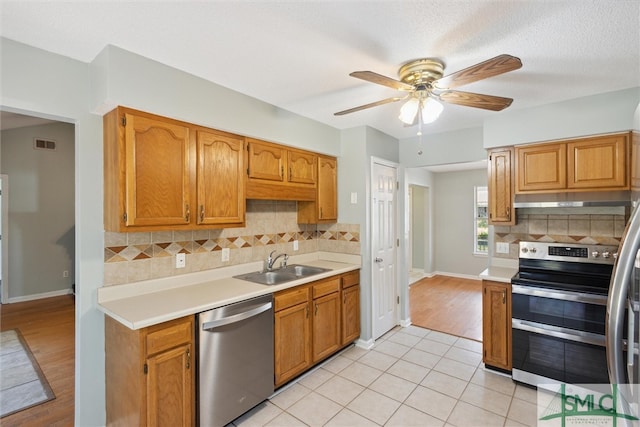 kitchen featuring backsplash, a textured ceiling, light hardwood / wood-style flooring, sink, and stainless steel appliances